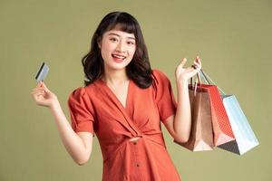 asiatisk kvinna som håller shoppingpåsen och håller upp ett bankkort foto