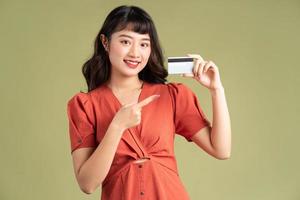 asiatisk kvinna som håller ett bankkort och pekar på bankkortet
