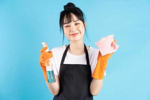 asiatisk hemmafru bär orange handskar och håller en spray med vatten i handen foto