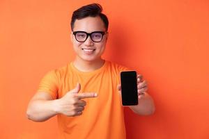 ung asiatisk man som håller telefonen med ett upphetsat uttryck foto