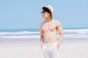 ung asiatisk man som går på stranden