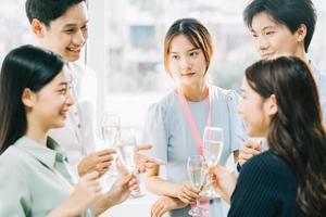 grupp asiatiska affärsmän har en skål tillsammans och chattar på en företagsfest foto