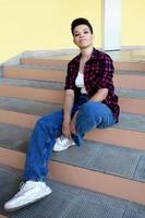 vacker afroamerikansk kvinna med kort hår, utanför sitter på trappan foto