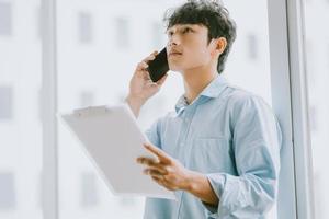 asiatisk affärsman ringer för att diskutera arbetet vid fönstret foto