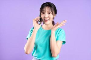 ung asiatisk flicka i cyanskjorta på lila bakgrund foto