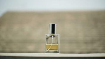 små transparent parfym flaska fylld med gul flytande på tabell med minimalistisk suddigt bakgrund. foto