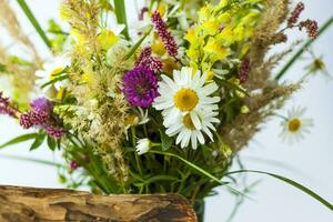 en torr stubbe, träd bark och en bukett av vild blommor i en små glas vas. eleganta utseende, layout, personlighet. foto