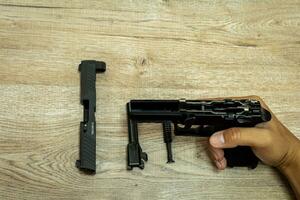 delar av ett automatisk pistol på en trä- tabell bakgrund. foto
