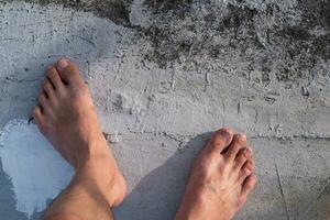 de ung mannens fötter flöt på en annorlunda cement golv. fötter är inte stark, behöver till vara försiktig foto