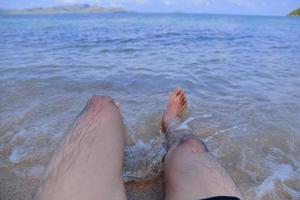 mannen är på stranden och fötterna i havet foto