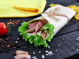 tortilla wrap sandwich med kött och vägetables på trä