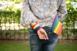 asiatisk dam som håller regnbågens färgflagga, symbol för lgbt pride-månaden firar årligen i juni socialt av homosexuella, lesbiska, bisexuella, transpersoner, mänskliga rättigheter. foto