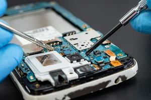 tekniker som reparerar insidan av mobiltelefonen med lödkolv. integrerad krets. begreppet data, hårdvara, teknik.