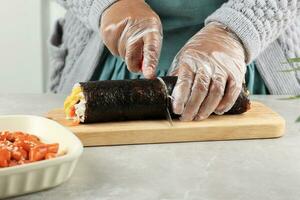 skära kimbap koreanska rulla ris med kniv. framställning gimbap foto
