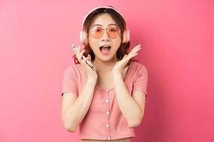 ung asiatisk kvinna som använder telefonen på rosa bakgrund