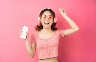 ung asiatisk kvinna som använder telefonen på rosa bakgrund