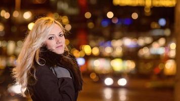 vacker, blond kvinna i bilbelysning i nattstaden. foto
