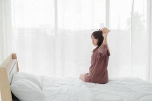 asiatisk kvinna i sängen och vaknar på morgonen