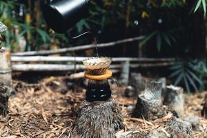 droppa kaffe i skogen, häll varmt vatten i kaffe foto