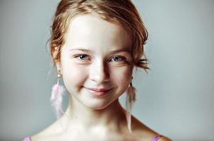 närbild porträtt av en ung flicka med festlig makeup för en fest. alla hjärtans dag. örhängen-fjädrar i öronen på modellen foto