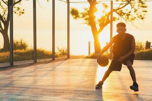 svart man håller på med sporter, spelar basketboll på soluppgång, aktiva livsstil, solig sommar morgon- foto