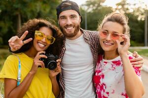 Lycklig ung företag av emotionell leende vänner gående i parkera foto