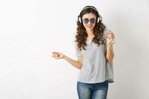 ung attraktiv kvinna lyssnande till musik på hörlurar, bär solglasögon, isolerat på vit bakgrund, foto
