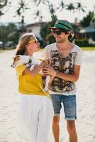 hipster ung eleganta hipster par i kärlek gående spelar hund valp domkraft russell i tropisk strand, vit sand, Häftigt utrusta, romantisk humör, har roligt, solig, man kvinna tillsammans, semester foto