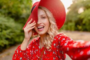 attraktiv eleganta blond leende kvinna i sugrör röd hatt och blus sommar mode foto