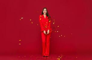 attraktiv kvinna fira jul på röd bakgrund i konfetti foto