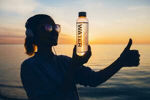 kvinna på hav innehav flaska av vatten foto