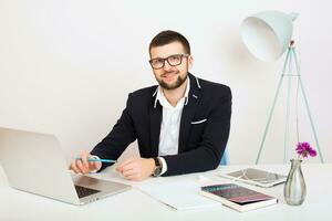 ung stilig eleganta hipster man i svart jacka arbetssätt på kontor tabell foto