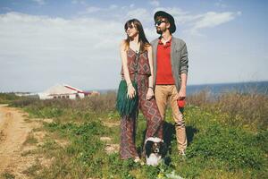 ung eleganta hipster par i kärlek gående med hund i landsbygden foto