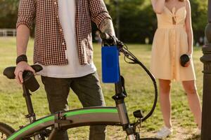 detaljer av hipster eleganta man i parkera lyssnande till musik på använder sig av elektrisk cykel foto