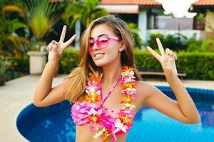 sexig kvinna på sommar semester har roligt på slå samman bär bikini och rosa solglasögon foto