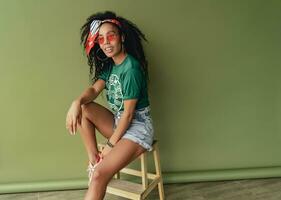 attraktiv svart afrikansk amerikan kvinna Framställ i eleganta hipster utrusta på grön bakgrund foto