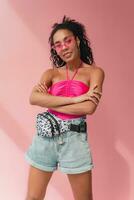 attraktiv svart afrikansk amerikan kvinna i eleganta utrusta på rosa bakgrund foto
