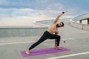attraktiv hansome man med atletisk stark kropp håller på med morgon- yoga asana utomhus foto