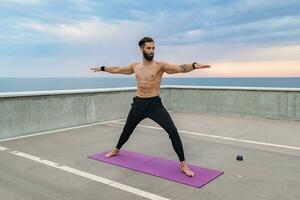 attraktiv hansome man med atletisk stark kropp håller på med morgon- yoga asana utomhus foto