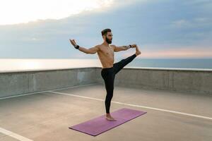 attraktiv hansome man med atletisk stark kropp håller på med morgon- yoga asana utomhus foto