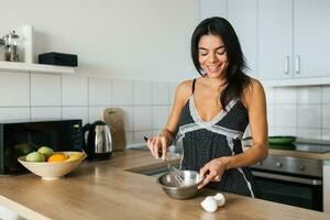 attraktiv leende kvinna i pyjamas har frukost i kök foto