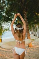 ung sexig kvinna i vit bikini baddräkt på tropisk strand foto