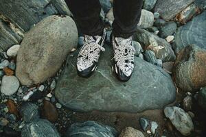 man gående på en sten på flod i vinter- skog skor närbild foto
