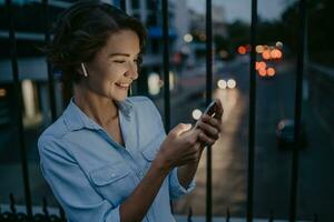 attraktiv eleganta kvinna gående i gata använder sig av smartphone foto