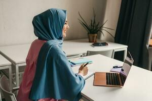 muslim kvinna i hijab arbetssätt i kontor rum foto