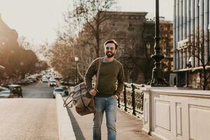 hipster man gående i gata med väska foto