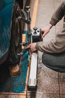 närbild av ett däck fastspänt av en planare som passerar den automatiska inriktningen av hjulen i garaget, garaget och verktygen för mekanikern.