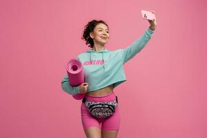 leende Lycklig skön kvinna i eleganta sporter utrusta Framställ på rosa bakgrund isolerat i studio foto