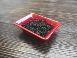kinesiskt te i liten röd tallrik på ett träbord. närbild foto