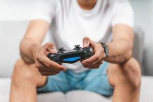 upphetsad ung stilig man som håller joystickkontrollen som spelar videospel som sitter i soffan hemma